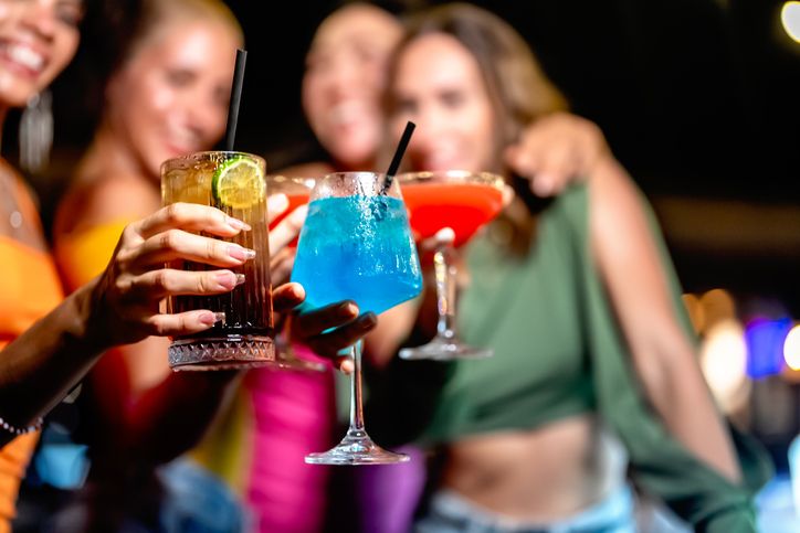 Group of friends toasting with colorful cocktails during a lively night out, showcasing vibrant drinks and festive vibes sip and play transportation